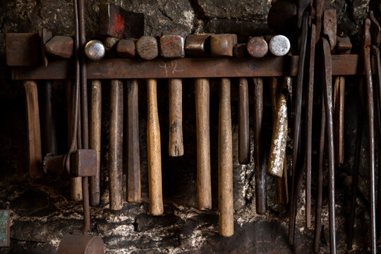 Row of blacksmiths hammers and tongs on workshop wall