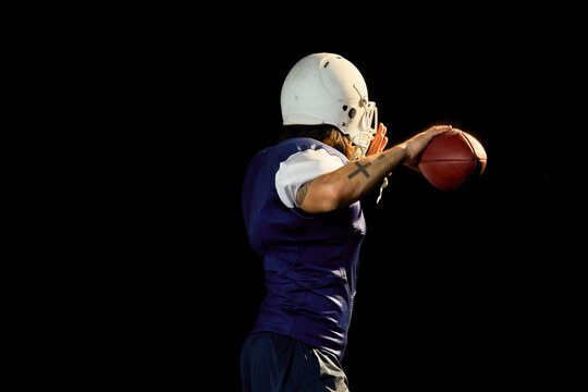 Portrait of quarterback with football, black background