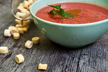Close-up view of Gazpacho bowl with parsley and extra virgin olive oil, accompanied by croutons around. Concept of mediterranean food, vegan, healthy.