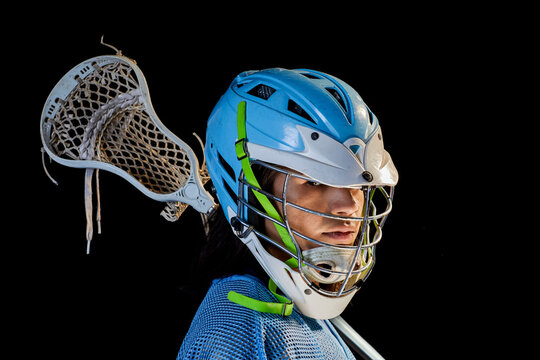 Young male lacrosse player with lacrosse stick, portrait against black background