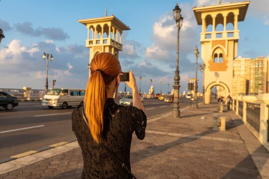 Female tourist with red hair photographing Stanley bridge, rear view, Alexandria, Egypt