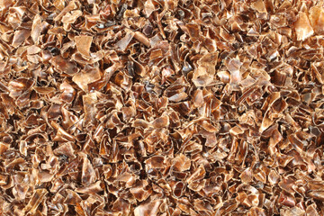 A heap of small pieces of chopped brown plastic bottles. View from above. Closeup