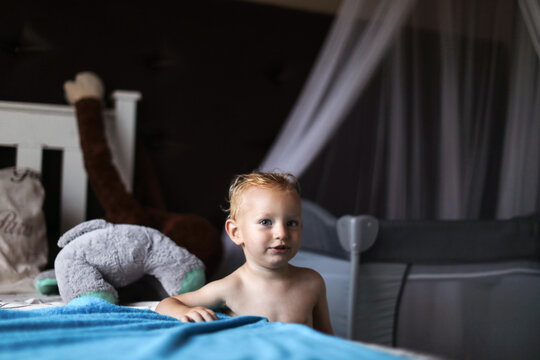Baby boy standing beside bed