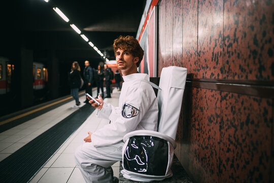 Astronaut using smartphone on train platform