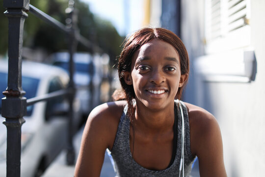 Young female runner on city sidewalk, head and shoulder portrait