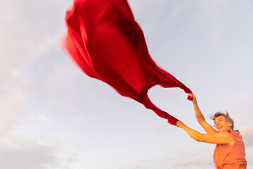 Woman holding up red cloth fluttering in wind