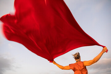 Woman holding up red cloth fluttering in wind