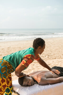 Woman massaging man on beach