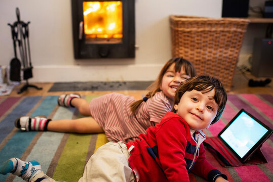 Girl and male toddler lying on living room rug posing for portrait
