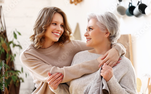 Happy senior woman with daughter hugging at home