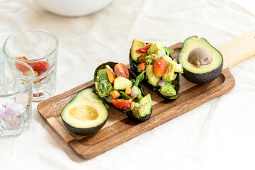 Avocado,tomato with fresh herbs in thai style salad in shell put on wooden tray.