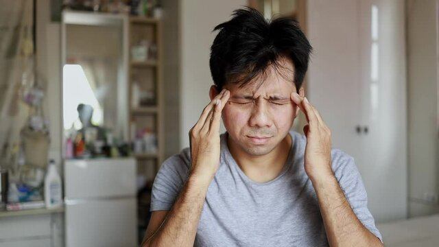 Young asian man has a headache in room, Man at home having a headache