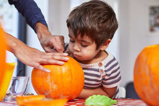 Boy looking at mother gut pumpkin in kitchen