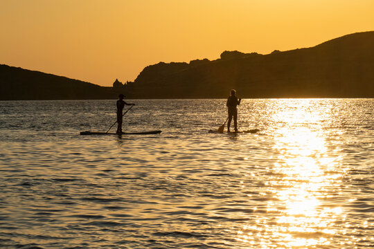 Mother and son standup paddleboarding in sea at sunset, Limnos, Khios, Greece