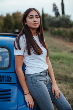 Portrait of woman leaning against car in countryside, Florence, Toscana, Italy