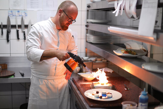 Chef Using Blow Torch In Kitchen