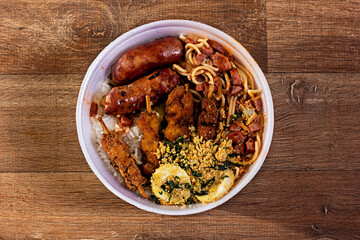 Marmitex - Tradicional Brazilian Meal with Sausage, eggs, spaghetti, rice, on a wooden table