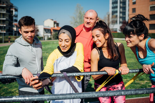 Calisthenics class at outdoor gym, men and women taking smartphone selfie