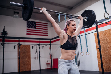 Young woman lifting barbell in gym