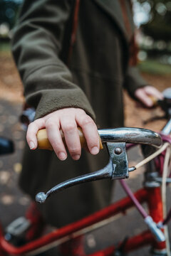 Young Woman Pushing Bicycle In Autumn Park, Close Up Of Hand On Handlebar