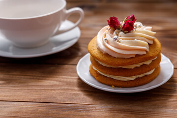 Sponge cake with cream, decorated with small flowers and a cup of tea.