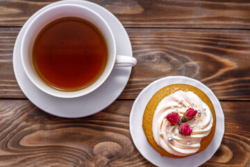 Sponge cake with cream, decorated with small flowers and a cup of tea.