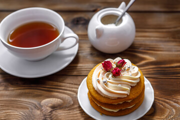 Sponge cake with cream, decorated with small flowers and a cup of tea.
