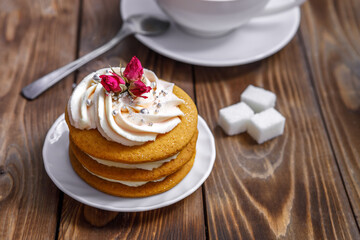 Sponge cake with cream, decorated with small flowers and a cup of tea.