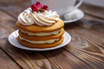 Sponge cake with cream, decorated with small flowers and a cup of tea.