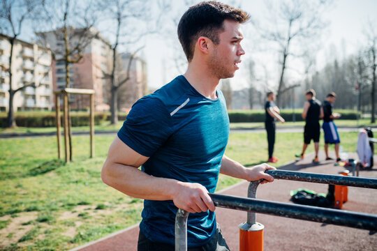 Calisthenics at outdoor gym, young man preparing to use parallel bars