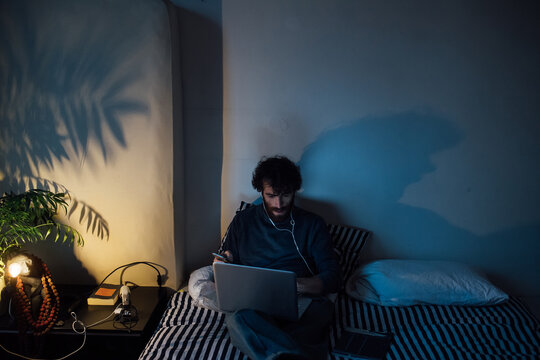 Bearded young man using laptop in bed