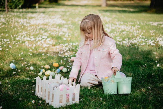 Cute girl sitting in field with easter eggs and basket, Arezzo, Tuscany, Italy
