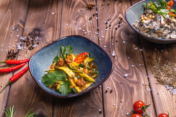 Vegetable salads in plates, cherry tomatoes, cinnamon, rosemary on a brown wooden background.