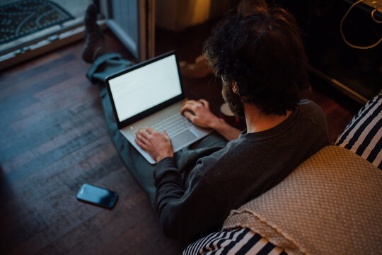 Bearded young man using laptop in bedroom