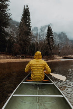 Young male canoeist rowing canoe on river, rear view, Yosemite Village, California, USA