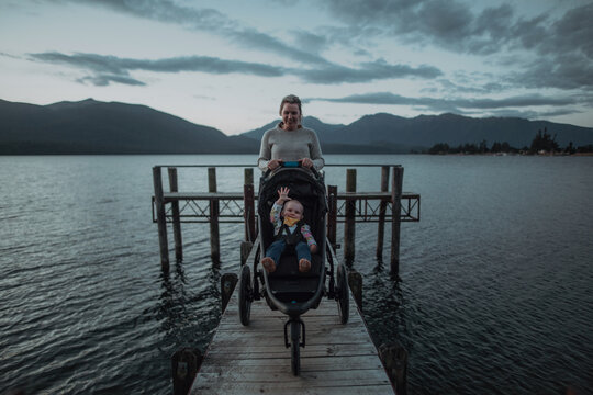 Mother with baby in pram on bridge by seaside, Te Anau, Southland, New Zealand
