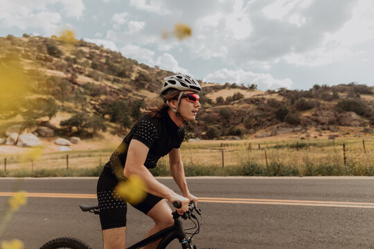 Young male cyclist cycling on rural road, side view, Exeter, California, USA