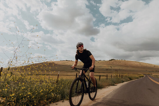 Young male cyclist looking away while cycling on rural road, Exeter, California, USA