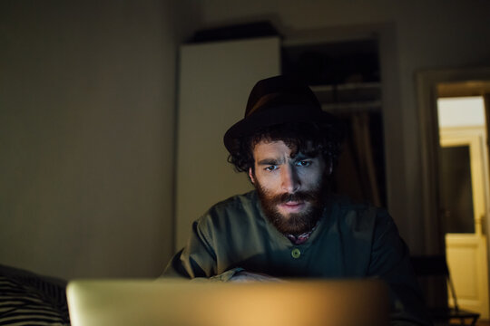 Bearded young man using laptop at home