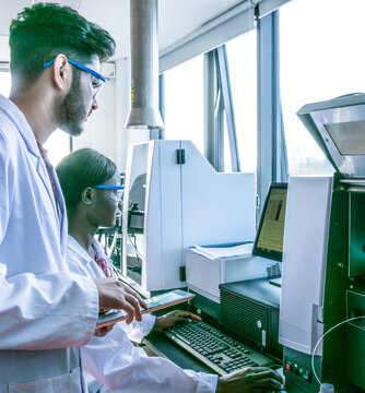 Young female and male scientists looking at computer in laboratory