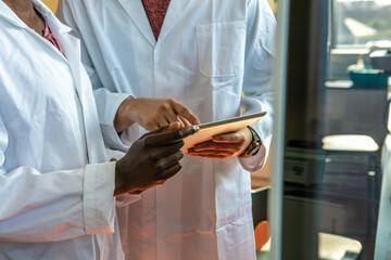 Young female and male scientists using digital tablet in laboratory, mid section