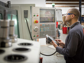 Knife factory worker operating machinery controls