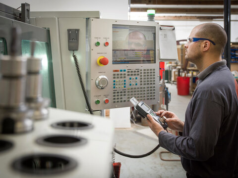 Knife factory worker operating machinery controls
