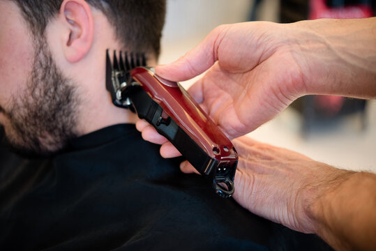 Hairdresser shaving customer's hair in barber shop