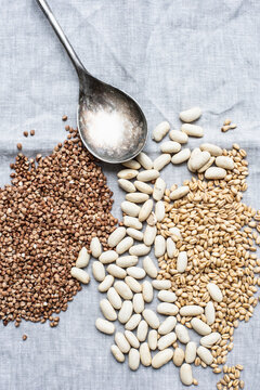 Still life of dessert spoon with lima beans, pearl barley and hemp seeds, overhead view