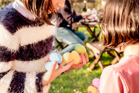 Two girl with handfuls of dyed easter eggs at table, cropped