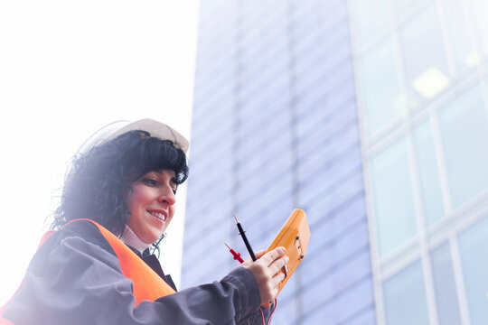Female surveyor looking at distance meter outside office building