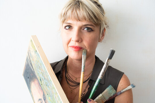 Portrait of fine art painter with painting and paint brushes
