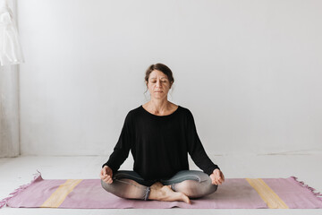 Woman sitting in lotus pose in yoga studio