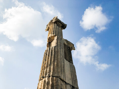 Ruins of ionic column against blue sky